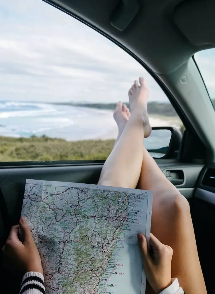A girl using a paper map on a road trip.