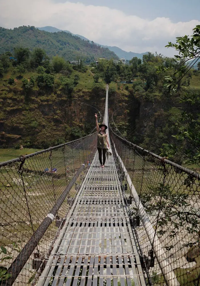 Monica on a suspension bridge surrounded by green nature - Is Nepal Safe for Solo Female Travel?