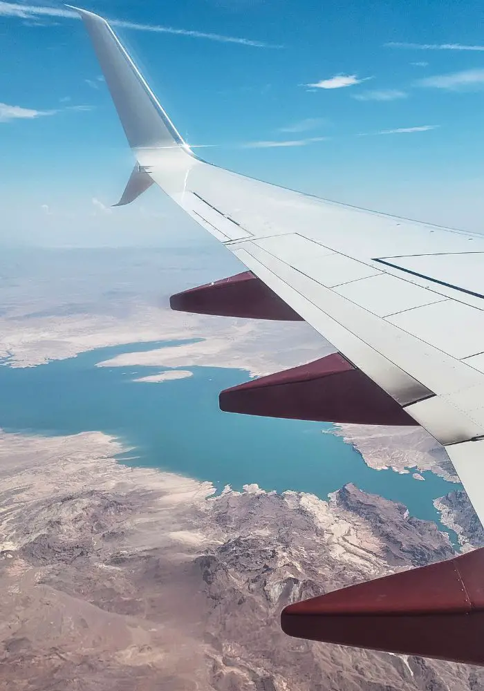 The wing of an airplane flying high above the desert.