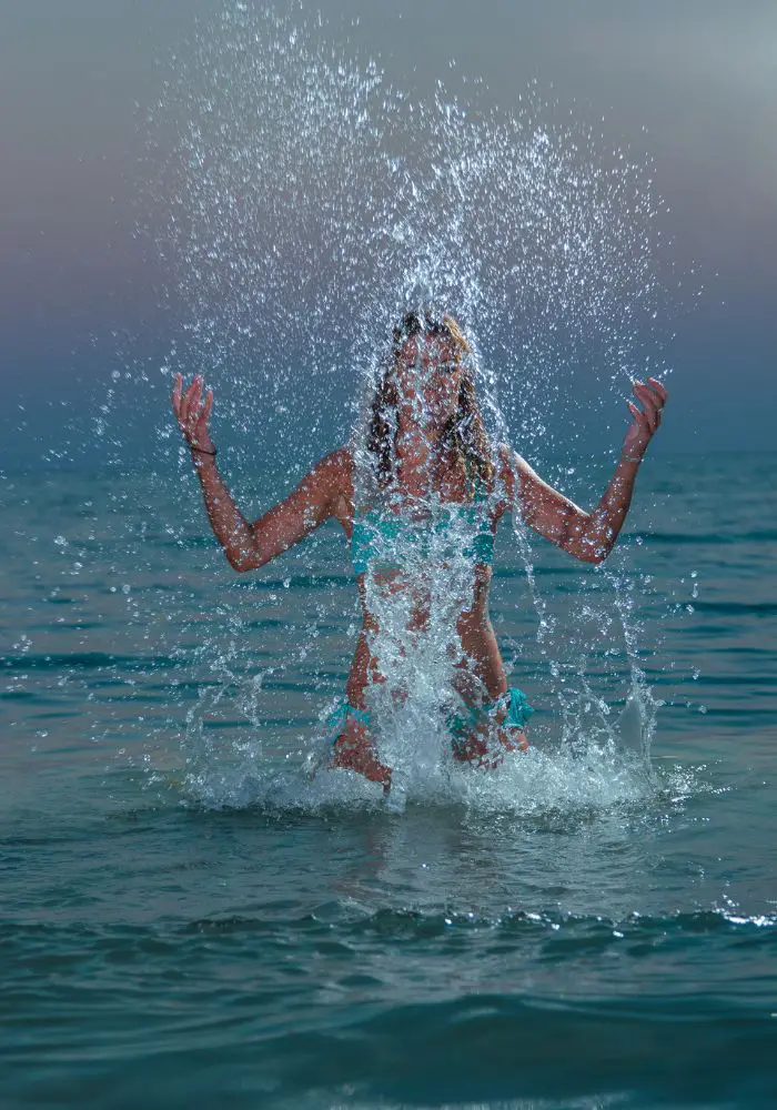 A girls plashing the Aruba waters at dusk - something you should never do, as it can attract sharks in Aruba.