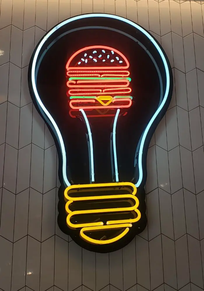 A neon sign with a light bulb and Big Mac, seen at the Big Mac Museum - one of the best things to do in Pittsburgh, PA.
