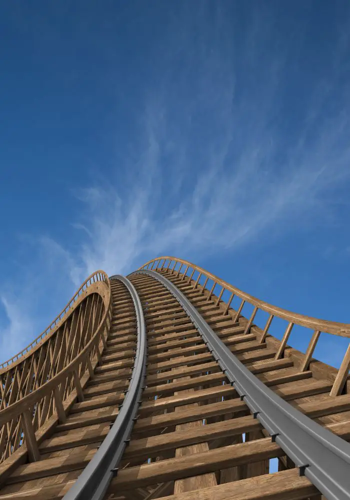 The fast curve of a roller coaster track against blue sky.