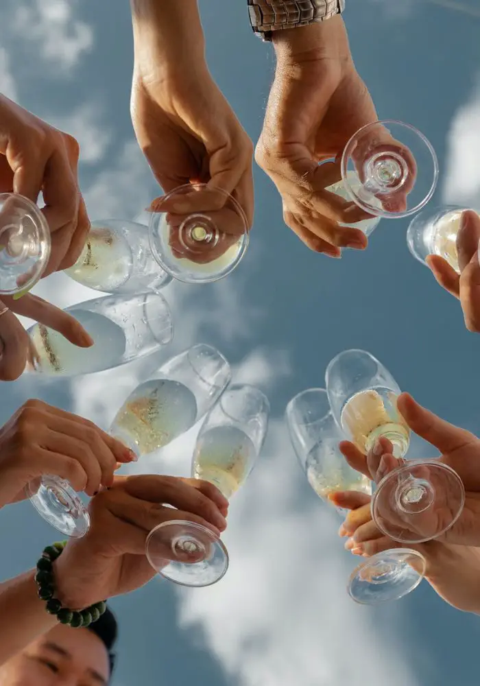 Friends toasting with champagne outdoors - Can You Buy Alcohol in Dubai? 