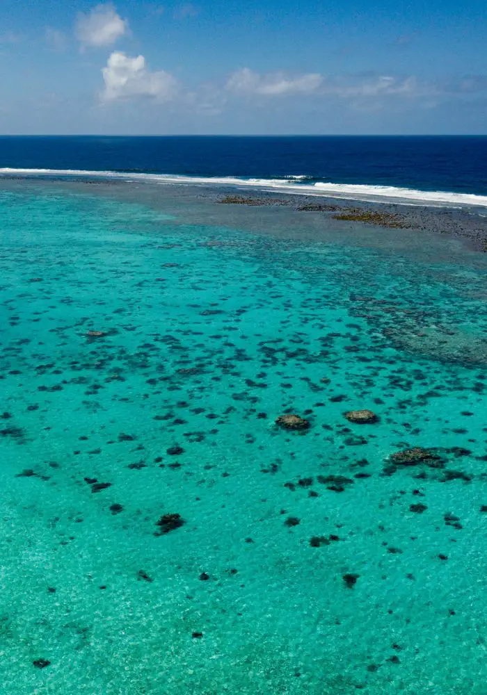 The turquoise water surrounding Rarotonga with coral and rocks contrasting the white sand.