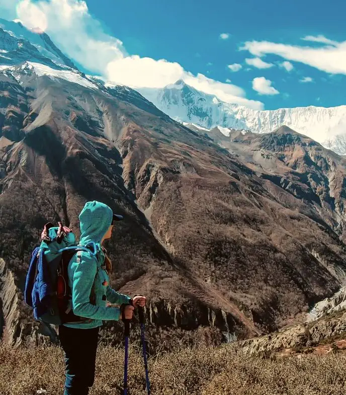 Girl in a blue jacket hiking during trekking season in Nepal.