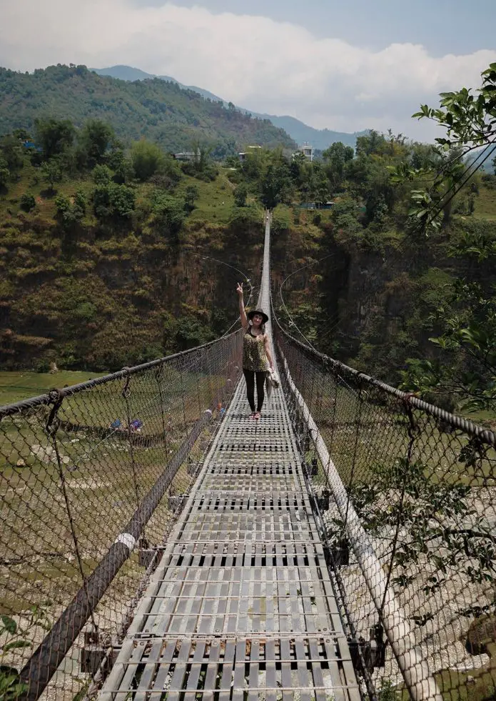 Monica crossing a suspension bridge in Nepal in May, one of the best seasons in Nepal for travel.
