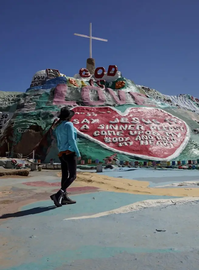 Monica in front of the brightly painted sculpture at Salvation Mountain, one of the best day trips from Palm Springs.