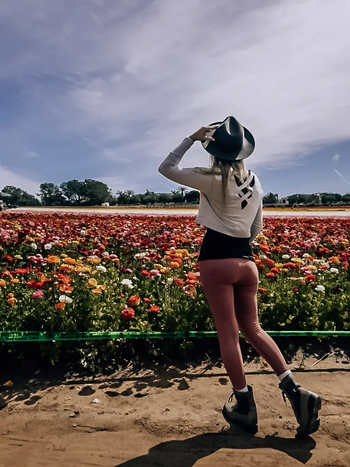 Monica in front of the colorful flower fields at Carlsbad, one of the best day trips from Palm Springs.