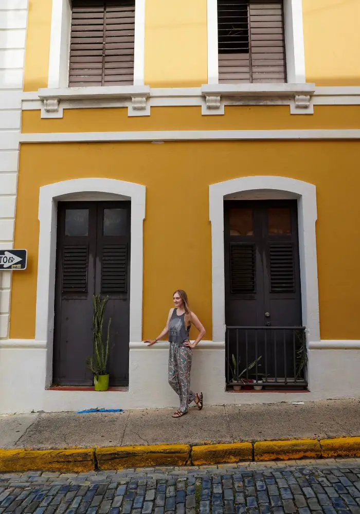 Monica in front of a bright yellow building in Puerto Rico, one of the best Caribbean islands close to Florida.