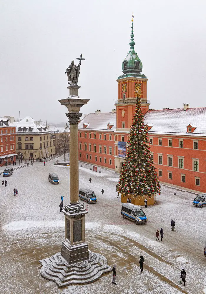 A light snow in Warsaw's Old Town in front of a tall Christmas Tree.