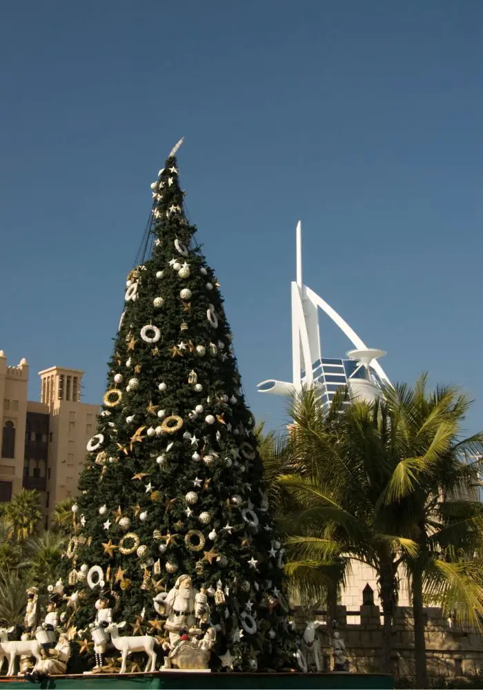 A decorated Christmas Tree next to the Burj Al Arab in Dubai during winter.