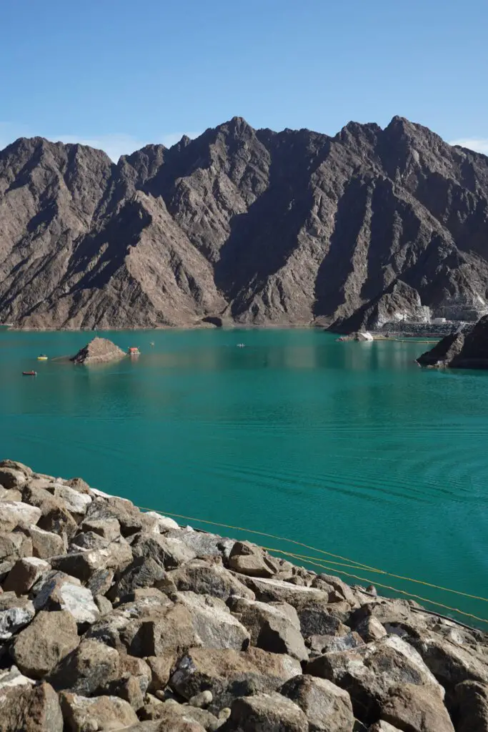 The blue green Hatta Dam in front of the Hatta Mountains, a great place for adventure during winter in Dubai.