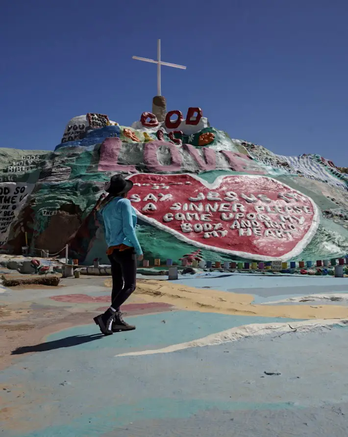 Monica next to the red, pink and green painted Salvation Mountain, one of the best weekend trips from San Diego.
