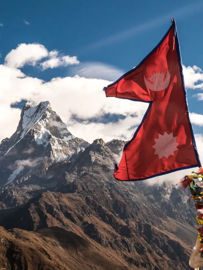 Nepal Trekking scenery of a snow covered mountain and a Nepal flag.