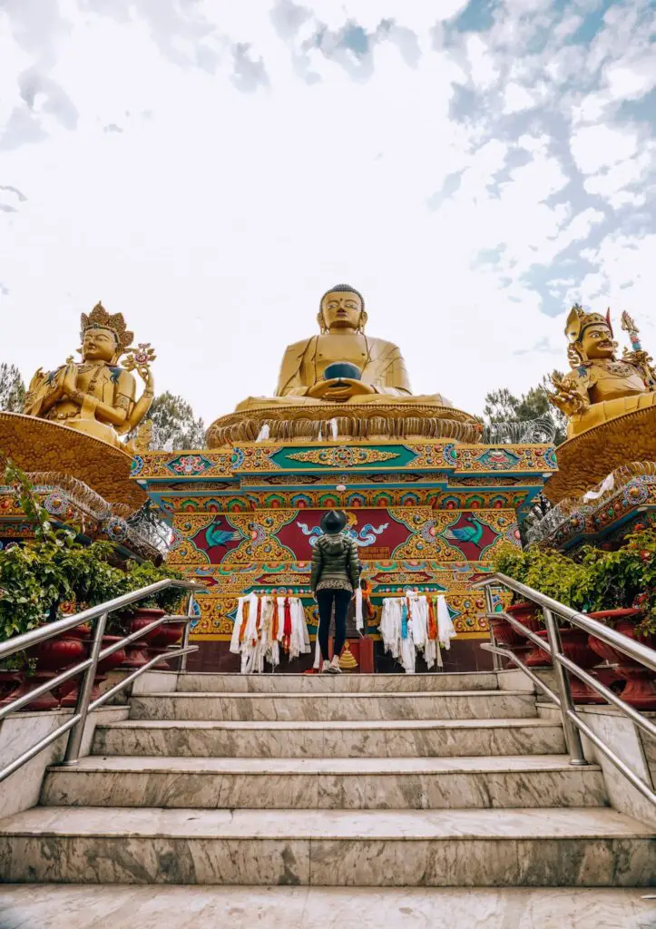 Monica looking at a golden Buddha statue in Kathmandu, where you will begin your Nepal trekking adventure.