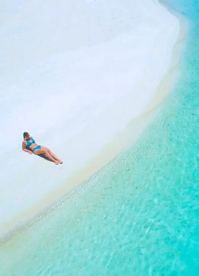 A girl on the white sand beach after flying from Rarotonga to Aitutaki on a Day Trip.