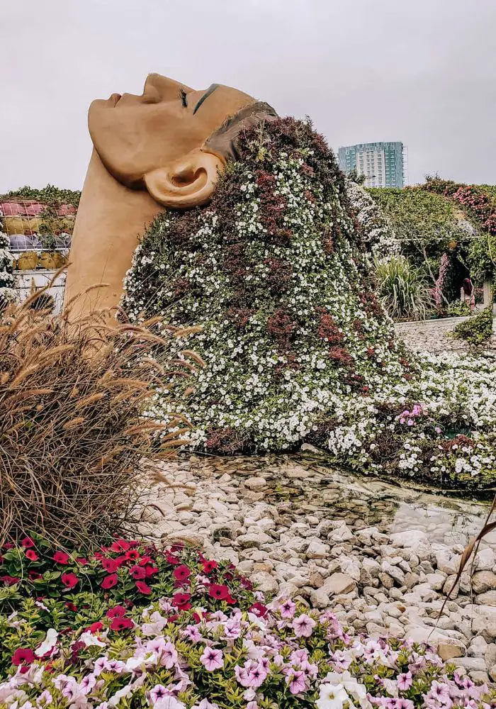 A flower-covered sculpture of a woman's head and neck at Dubai Miracle Garden, a great place to visit in Dubai's winter.