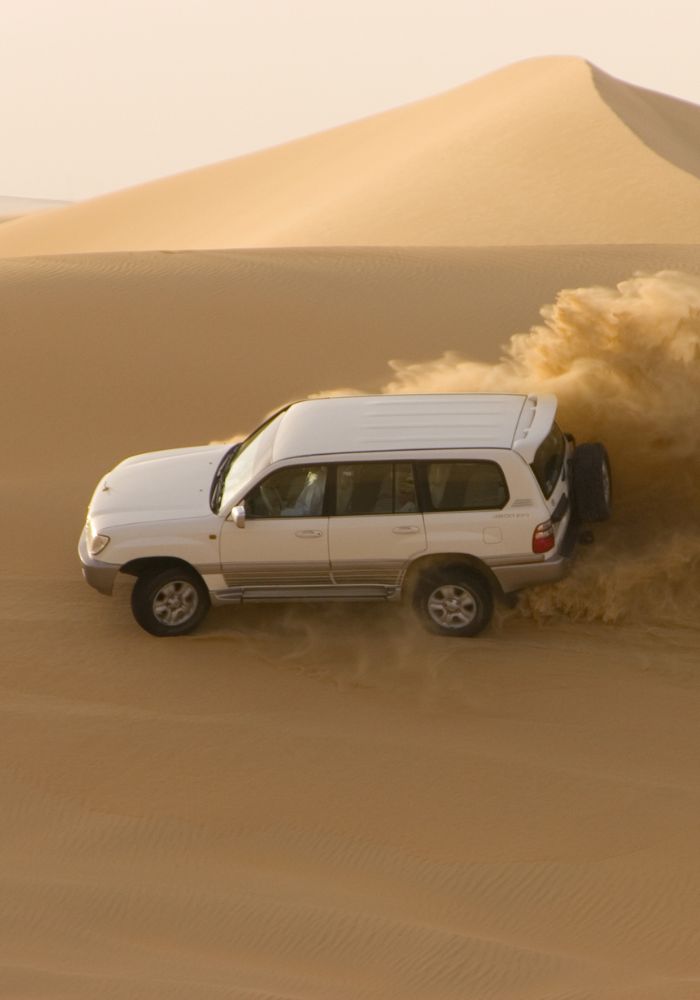 A white 4WD truck driving on the dunes for a safari - the perfect activity for winter in Dubai.