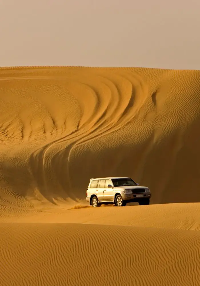 A desert safari vehicle on orange dunes, one of the top experiences to try when Visiting Abu Dhabi as a Woman.