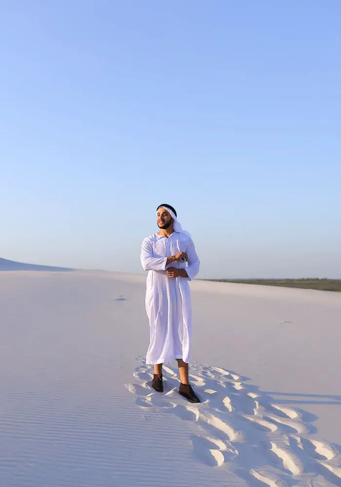 A male in white clothing in the Abu Dhabi desert.