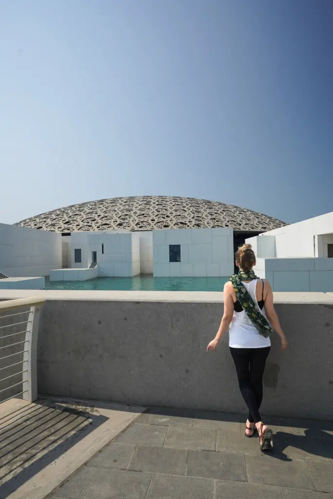 Monica outside of the Louvre Abu Dhabi's intricate architecture, a top place to see when Visiting Abu Dhabi as a Woman.
