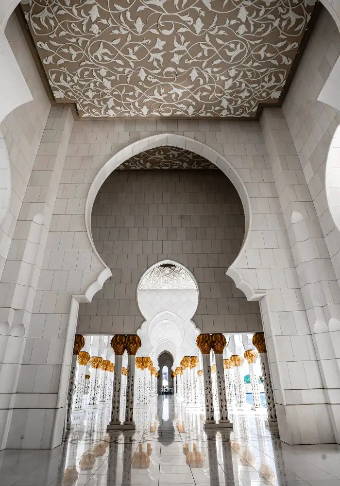 The white and gold façade of the Gran Mosque, one of the top places to see when Visiting Abu Dhabi as a Woman.