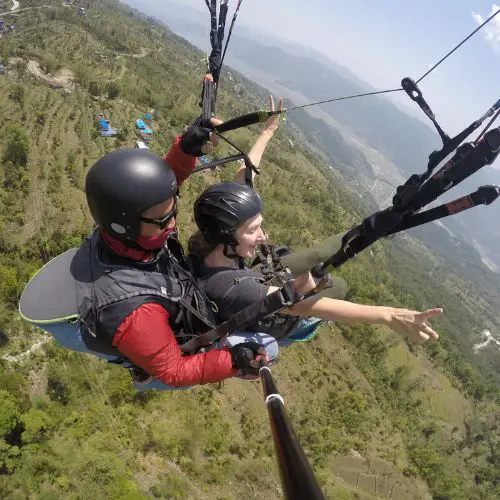 Monica paragliding in Nepal, an extreme activity where travel insurance, an essential travel safety item, should be considered.