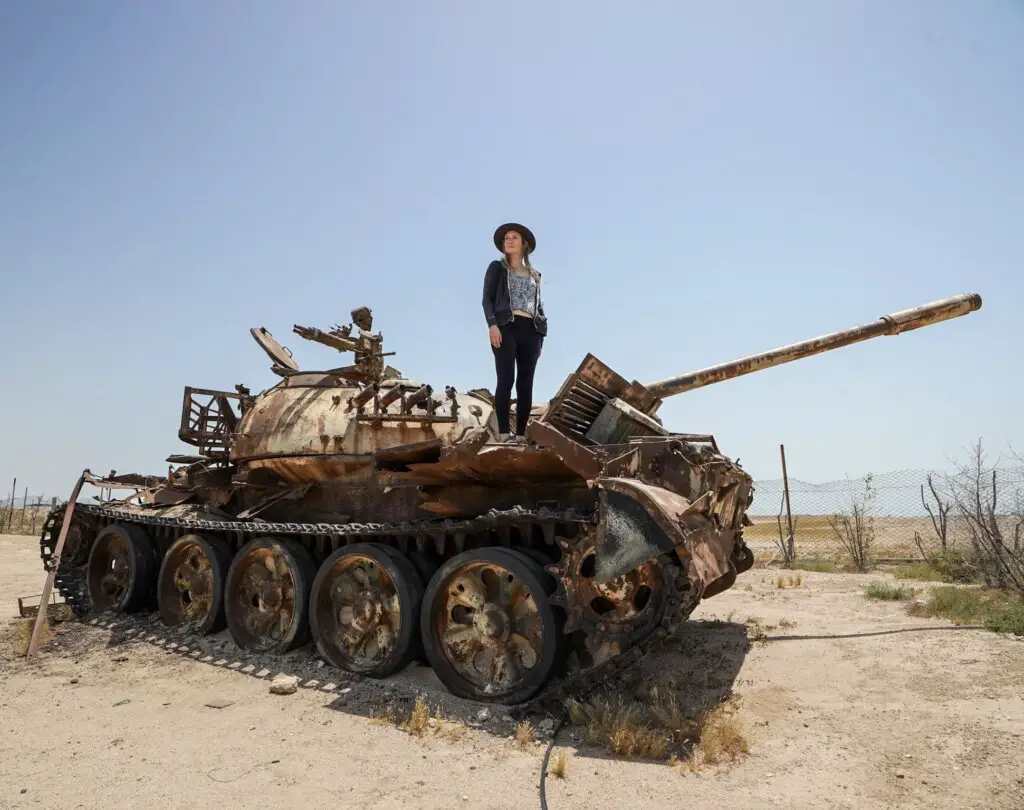 Girl standing on top of an abandoned Iraqi tank on Failaka Island, Kuwait.