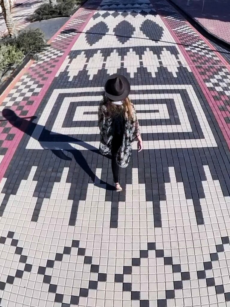 Girl walking down the colorful Sadu Street, with black and red and white bricks.