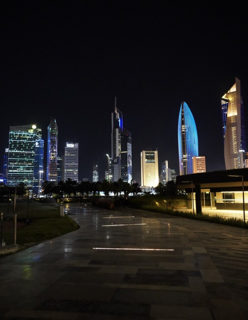 Al Shaheed Park at night, with colorfully lit buildings in Kuwait City.