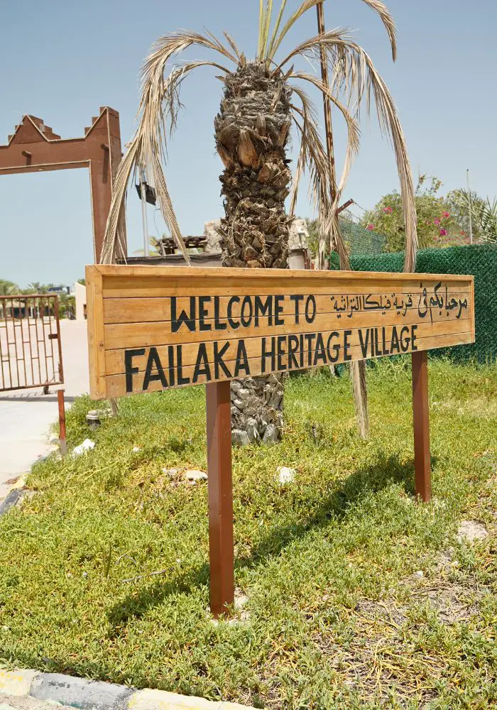 A yellow sign stating "Welcome to Failaka Heritage Village" seen on a Failaka Island day trip.