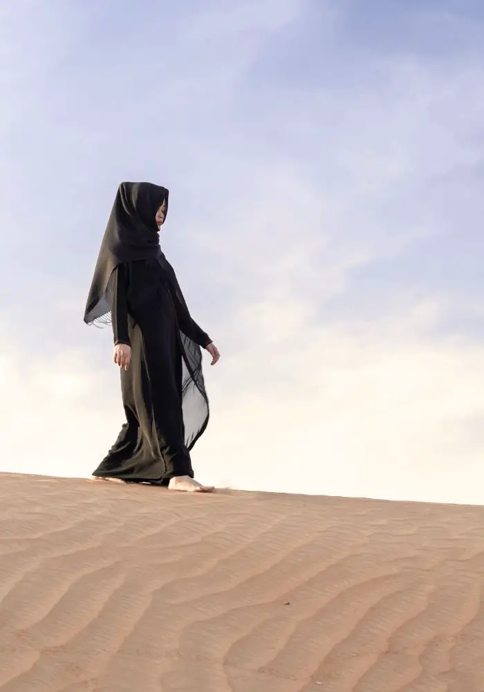 A girl wearing a long, black flowy abaya, like what the local women wear in Kuwait.