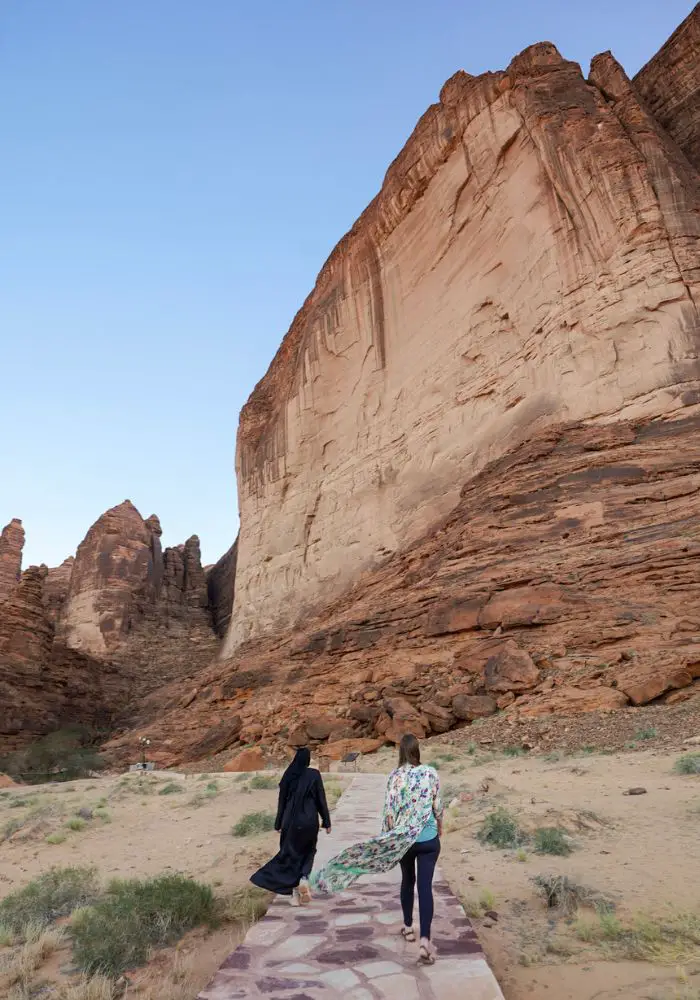 Two women walking toward Jebel Ikmah in Alula, one of the best attractions.