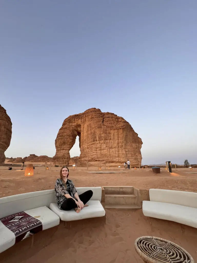 Monica on cushioned seat at dusk in front of Elephant Rock, one of the best things to see in AlUla Saudi Arabia.