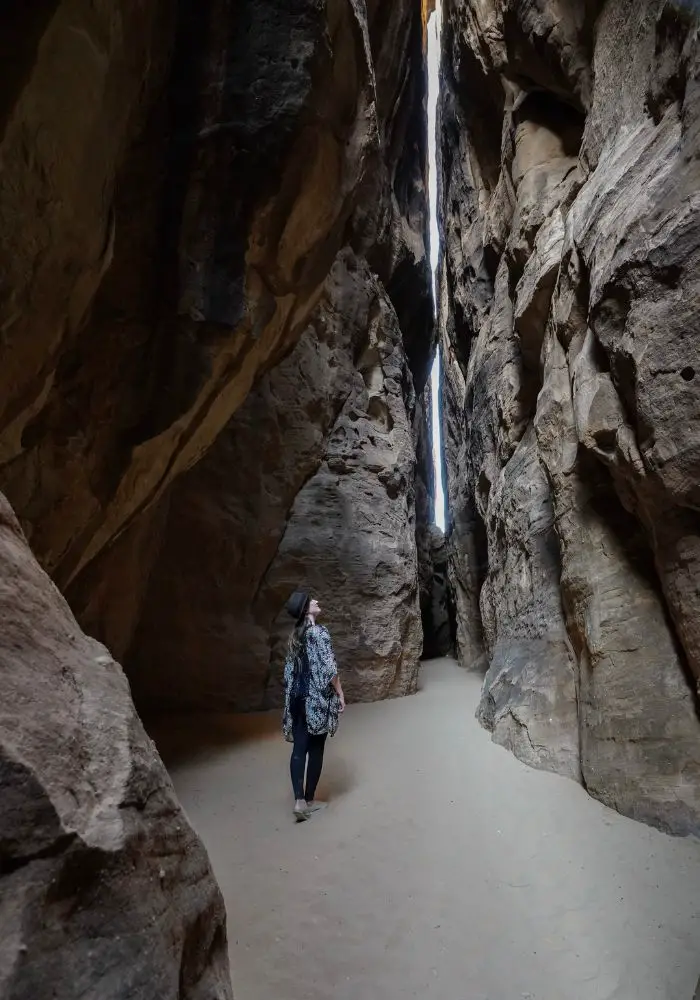 Monica looking up at towering rock walls and a slot canyon.