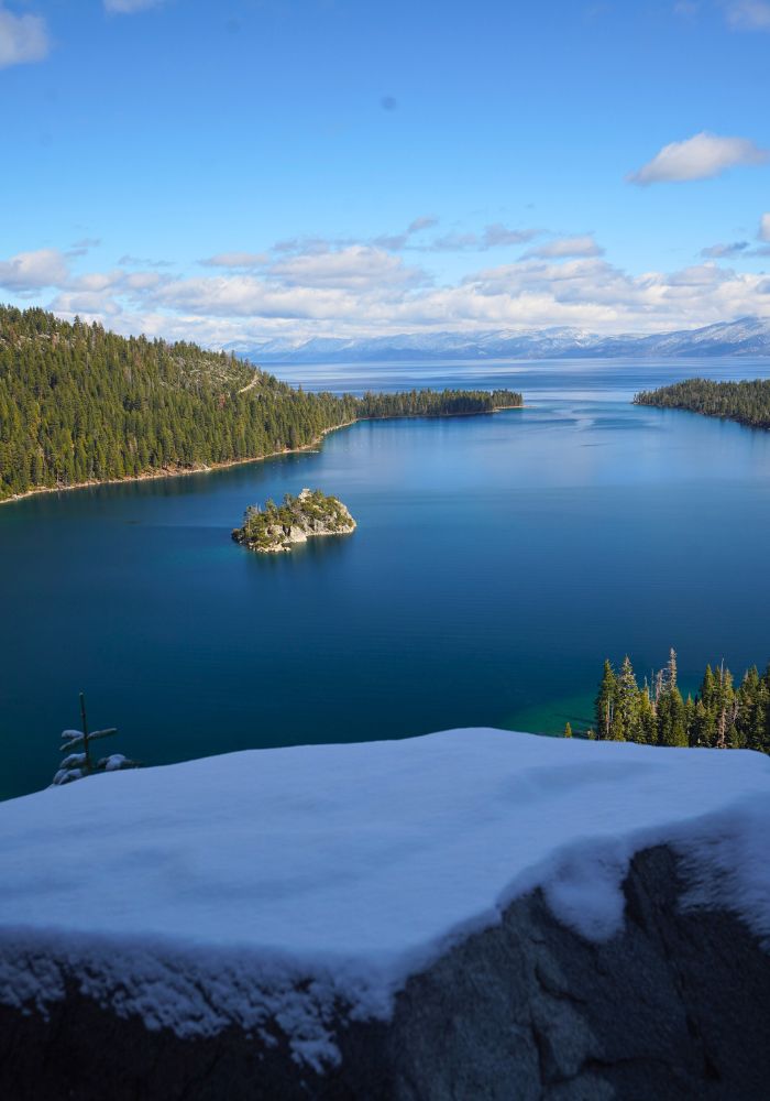 The deep blue hue of Lake Tahoe surrounded by green pine trees.