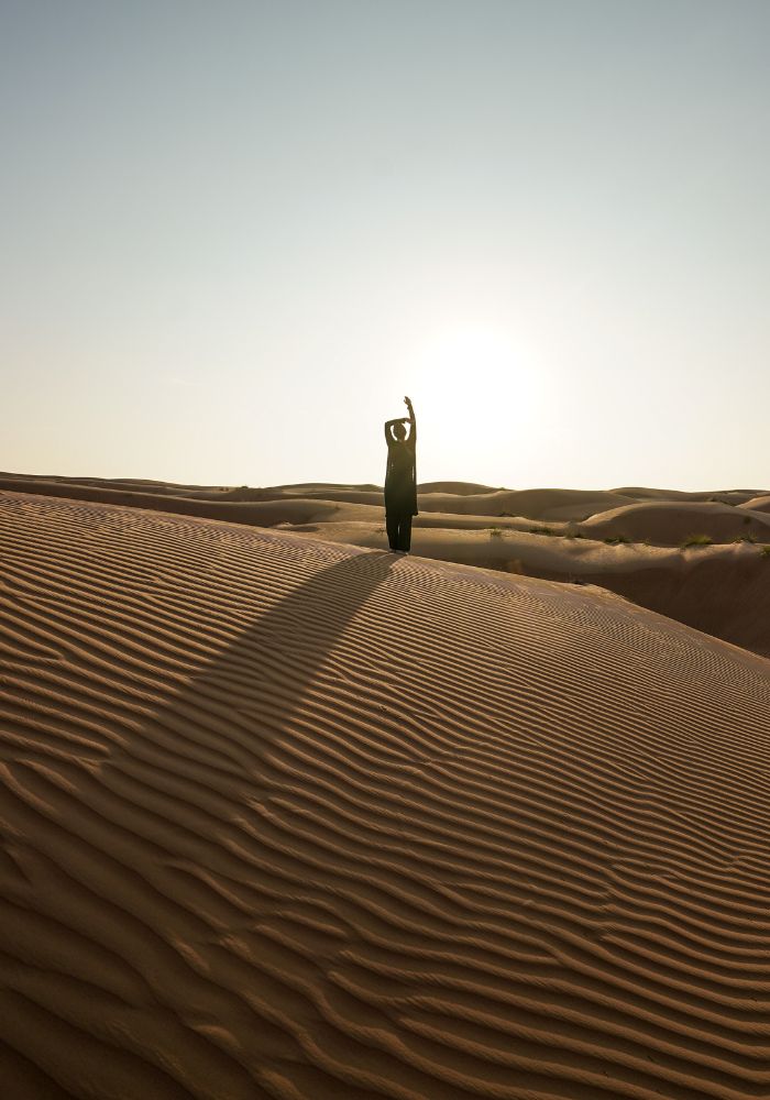 Monica standing on an orange sand dune at sunrise in Wahiba Sands, one of the best Muscat Day Trips!