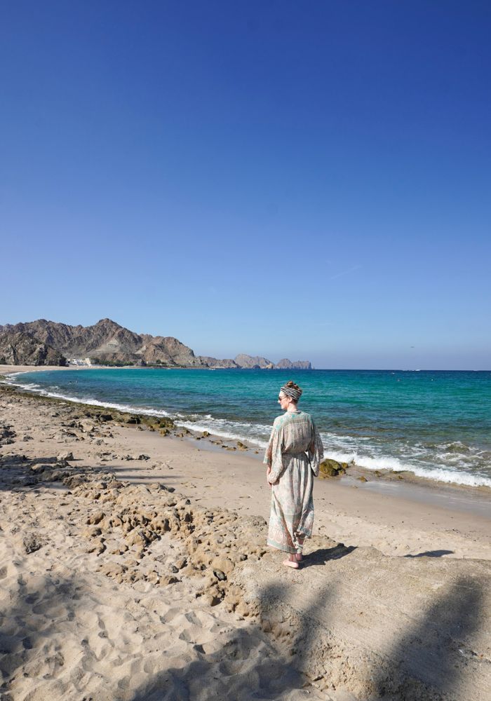 Monica on a sandy beach in Oman, dressing in a long kimono as part of her women's packing list.