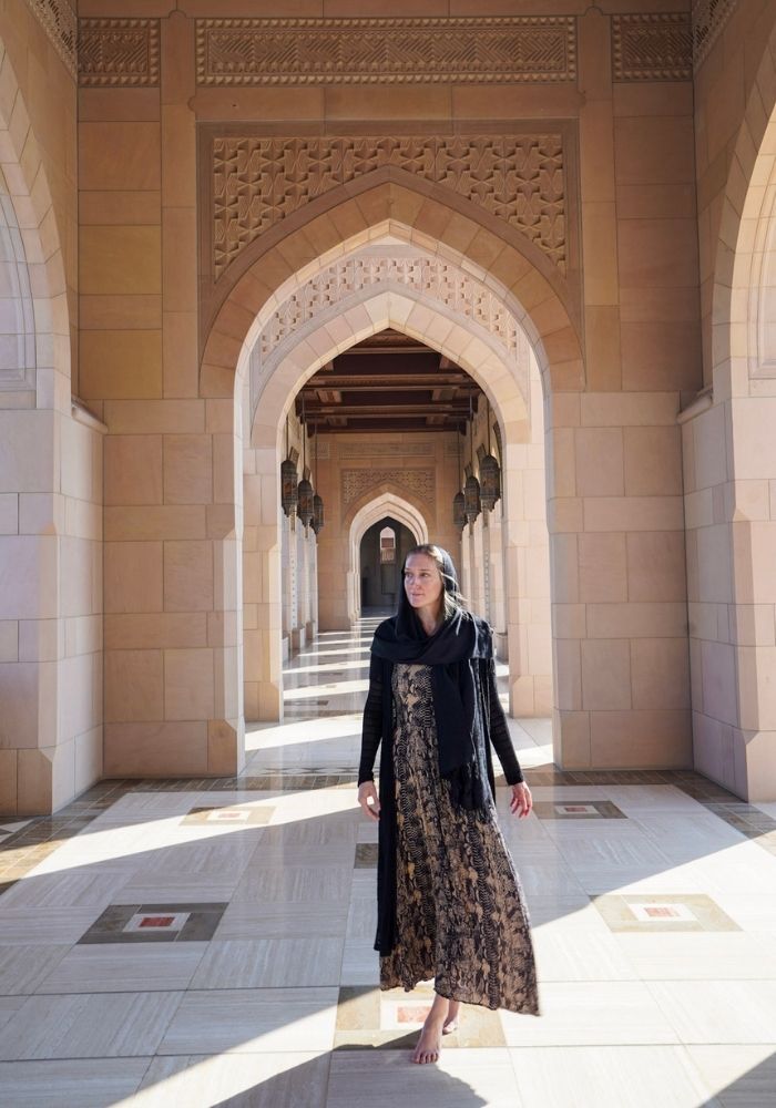 Monica walking through the Sultan Qaboos Grand Mosque - one of the best places to visit in Oman.