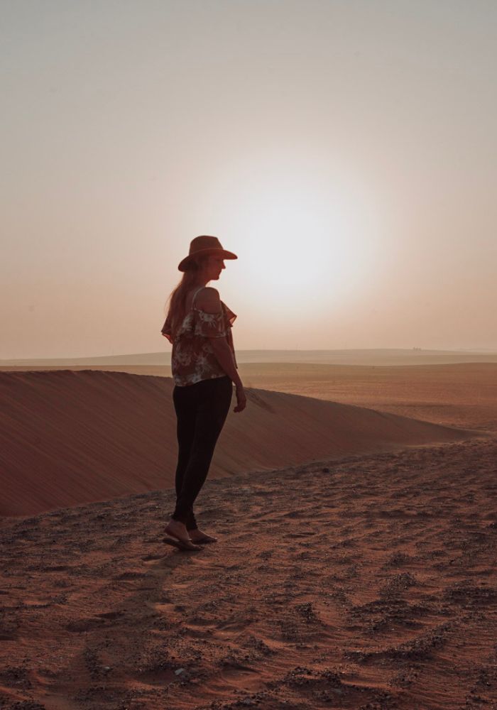 Monica strolling through the desert at sunrise, one of the best places to go when travbudget.eling Dubai on a 