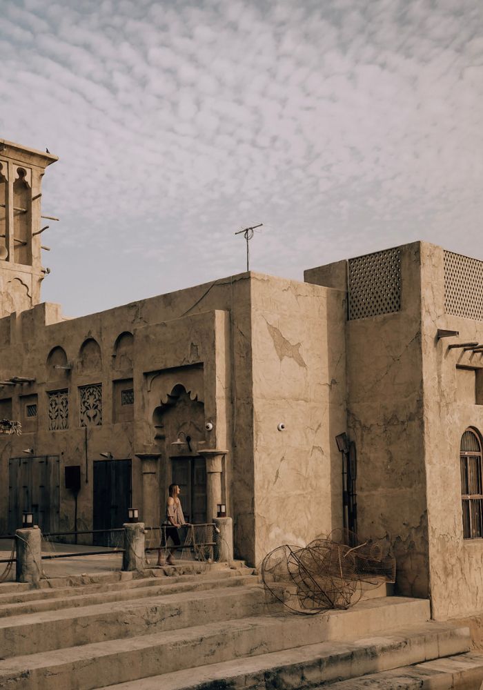 Monica standing in front of the tan buildings in Al Seef, a top place to visit when traveling Dubai on a budget.