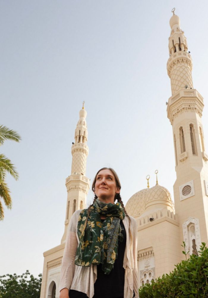 Monica in a green scarf, standing in front of the white Jumeirah Mosque.