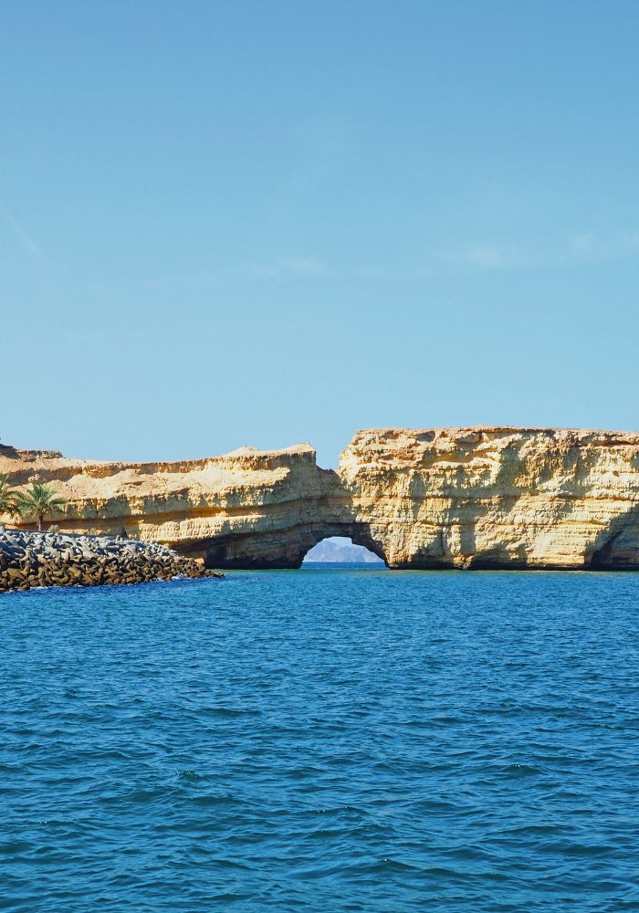 The large rock arch seen off the coast of Muscat's beach.